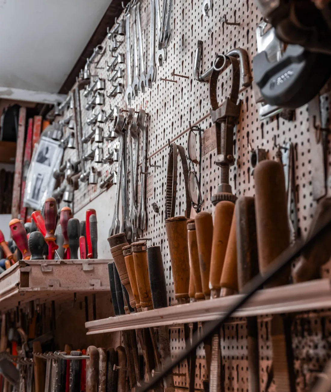 A workshop pegboard wall lined with screwdrivers, wrenches and hand tools