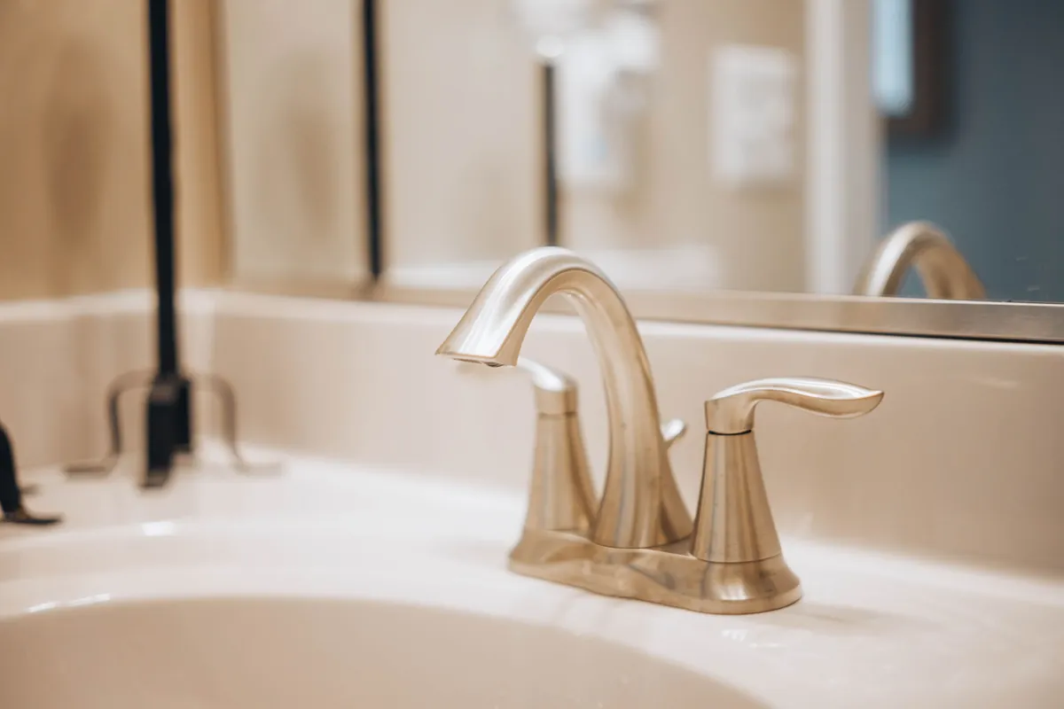 A brushed-gold bathroom faucet on a freshly installed vanity sink
