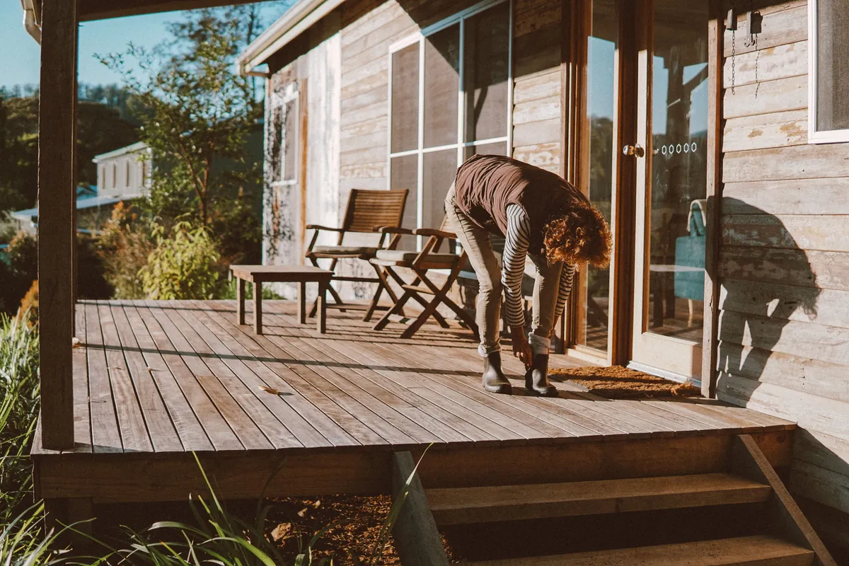 A wooden porch deck with new steps on a cedar-sided house in late-afternoon sun